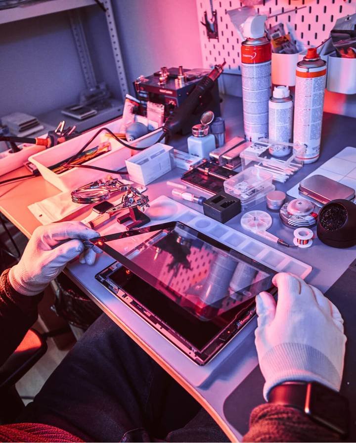 Technician repairing a tablet screen at a repair bench